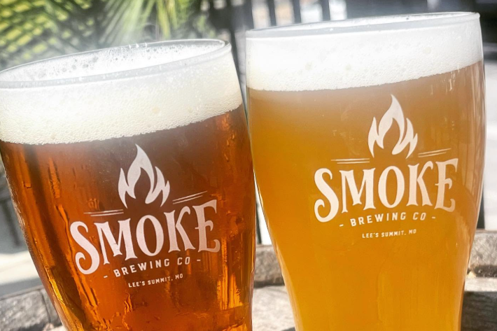 two glasses of beer with a smoke brewing co logo